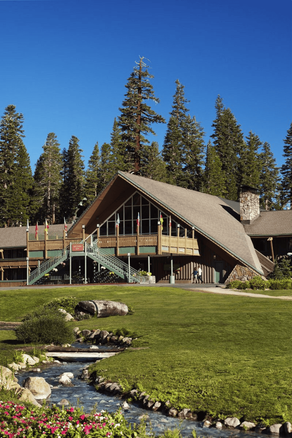 Scenic Lodge in Forested Mountain Area with Stream and Clear Blue Sky.
