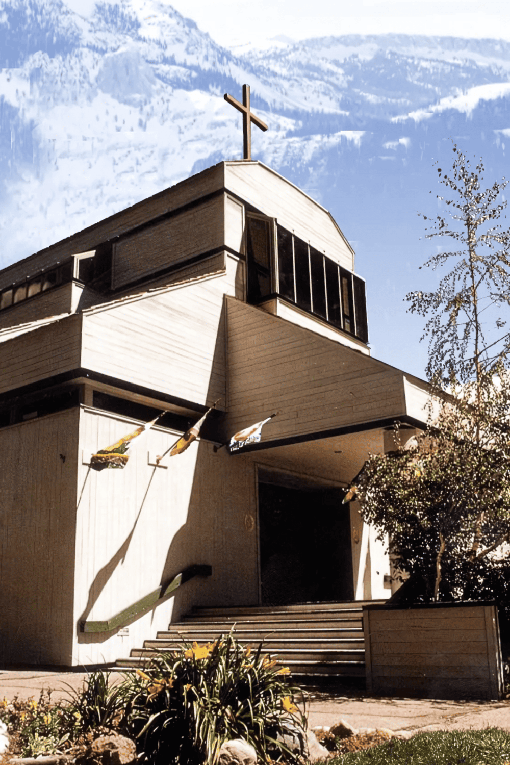 Modern church building with cross on top and mountain background, offering spiritual guidance and community support.