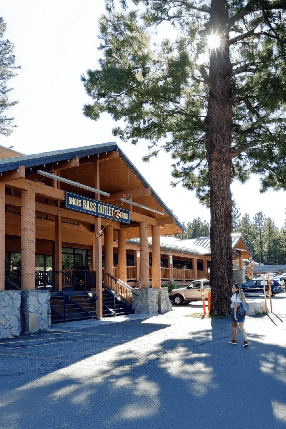 Charming outdoor shopping center with a Shoes Bass Outlet store and tall trees under sunny skies.