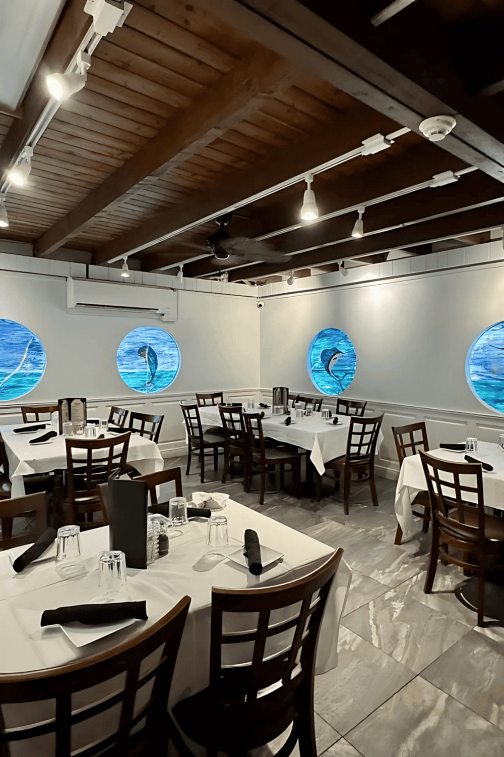 1. Bright seafood restaurant interior with ocean-themed wall art and wooden ceiling.