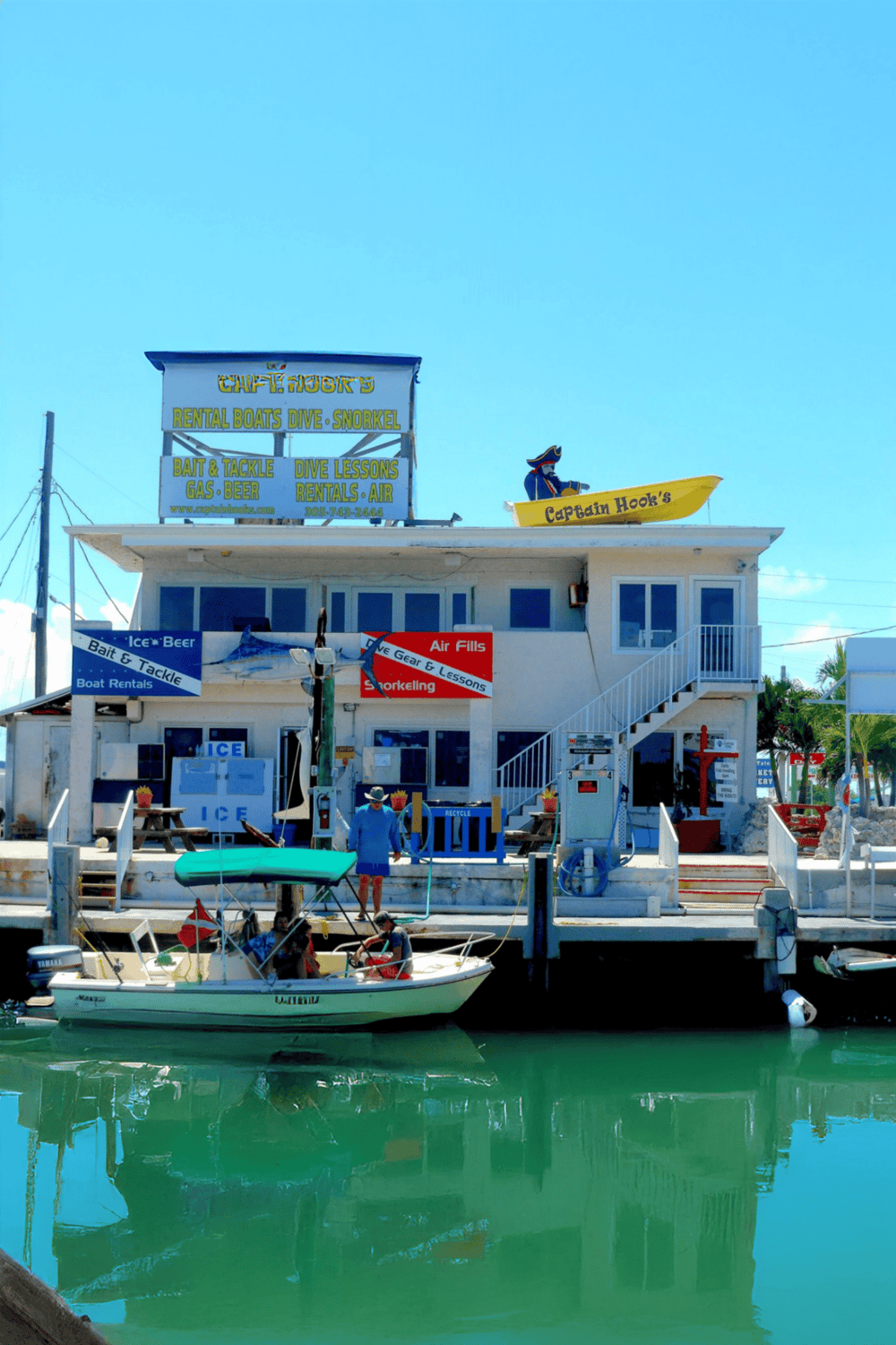 Boat rental and snorkeling shop on waterfront with boats and signage, perfect for aquatic adventures.