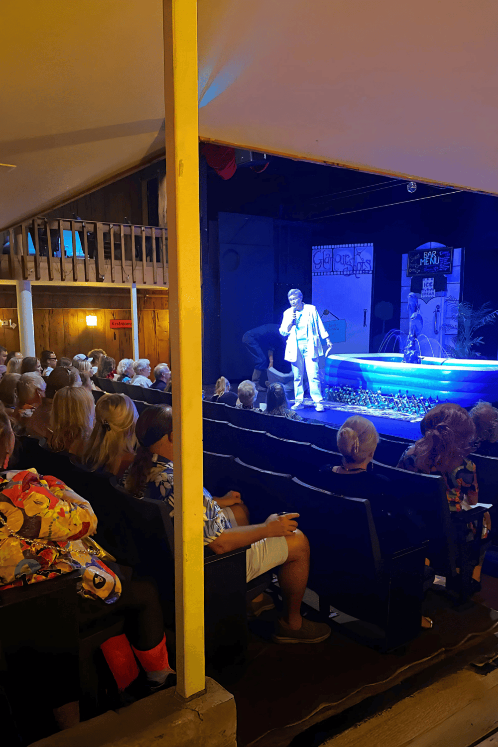 1. Audience watching live comedy show at Quest For Directions venue, featuring stage and performer.