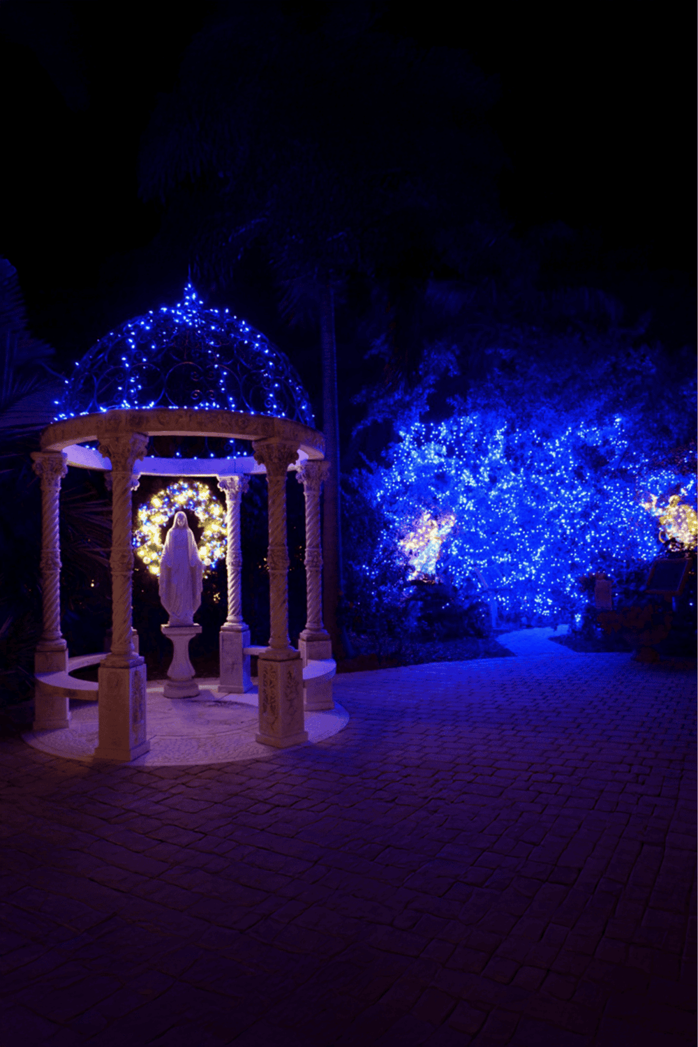 Blue holiday lights illuminating religious monument at night.