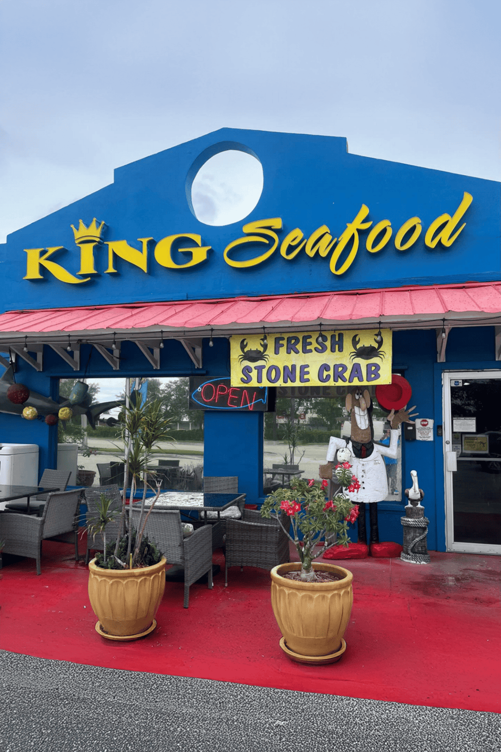Colorful seafood restaurant exterior with signage, outdoor seating, and decorative plants.