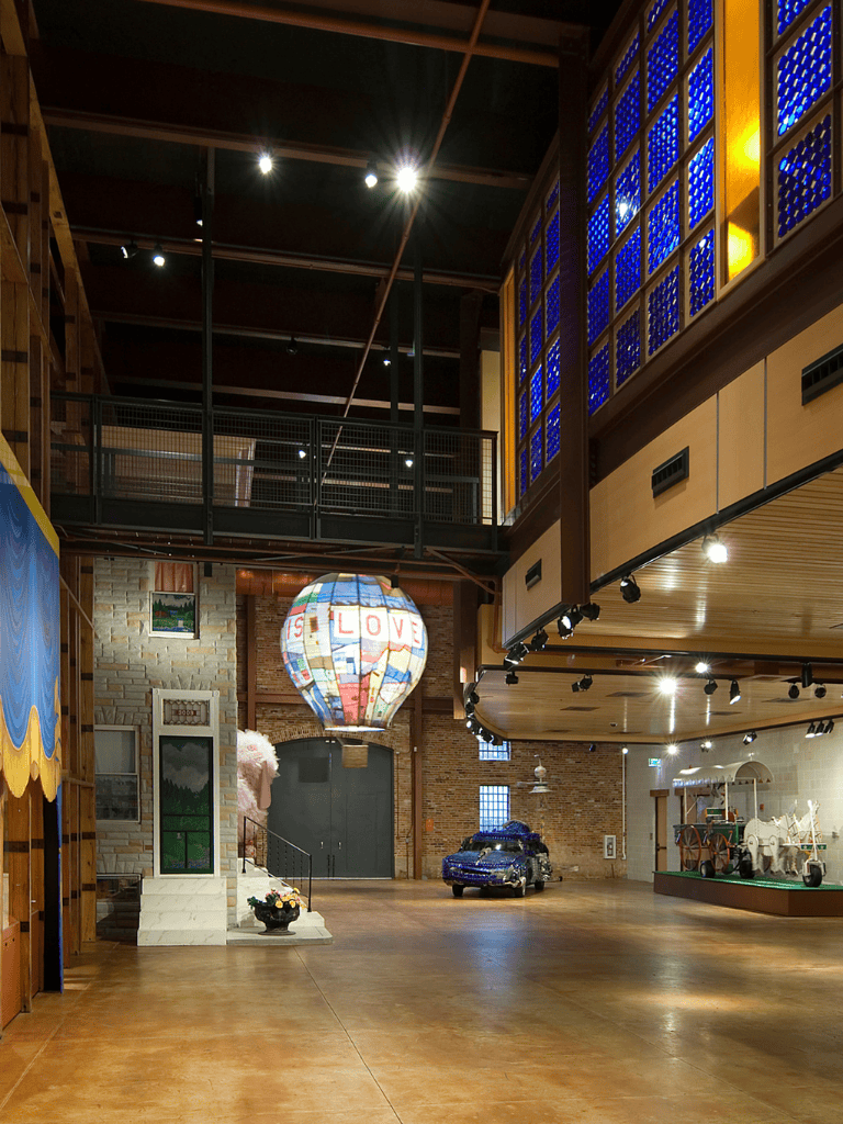 Colorful stained glass chandelier with the word "LOVE" in a modern indoor event space, showcasing art decor and vehicle exhibits.