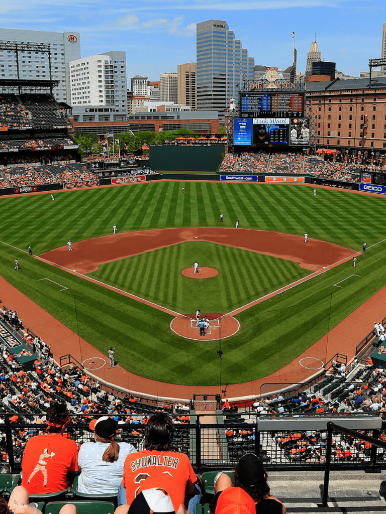 Empty baseball stadium with city skyline view and fans in foreground, perfect for sports event SEO.