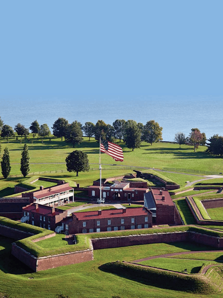 Aerial view of Fort Sumter with the American flag, lush green fort grounds, and scenic waterfront backdrop.