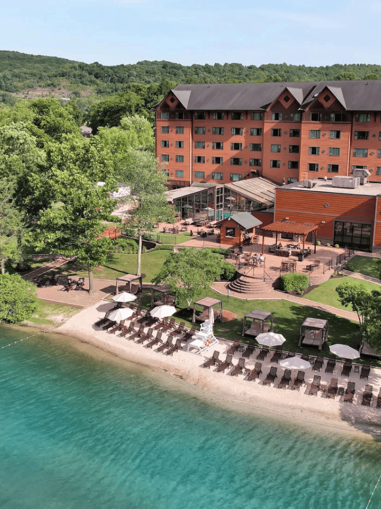 Cozy lakeside resort with outdoor pool, beach, and lush green surroundings for vacation relaxation.