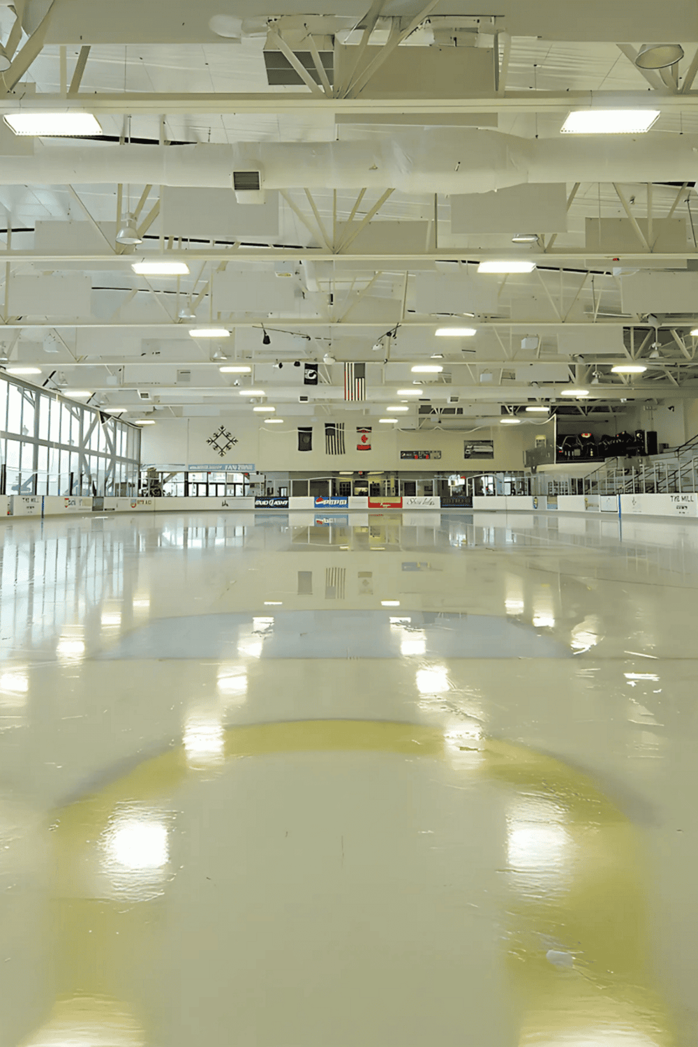 Bright indoor ice skating rink with polished ice and high ceilings.