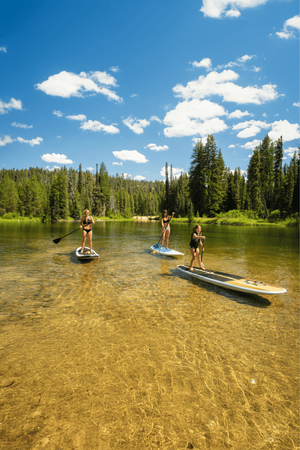 Sup activities on stand-up paddleboards in a mountain lake with forest surroundings.