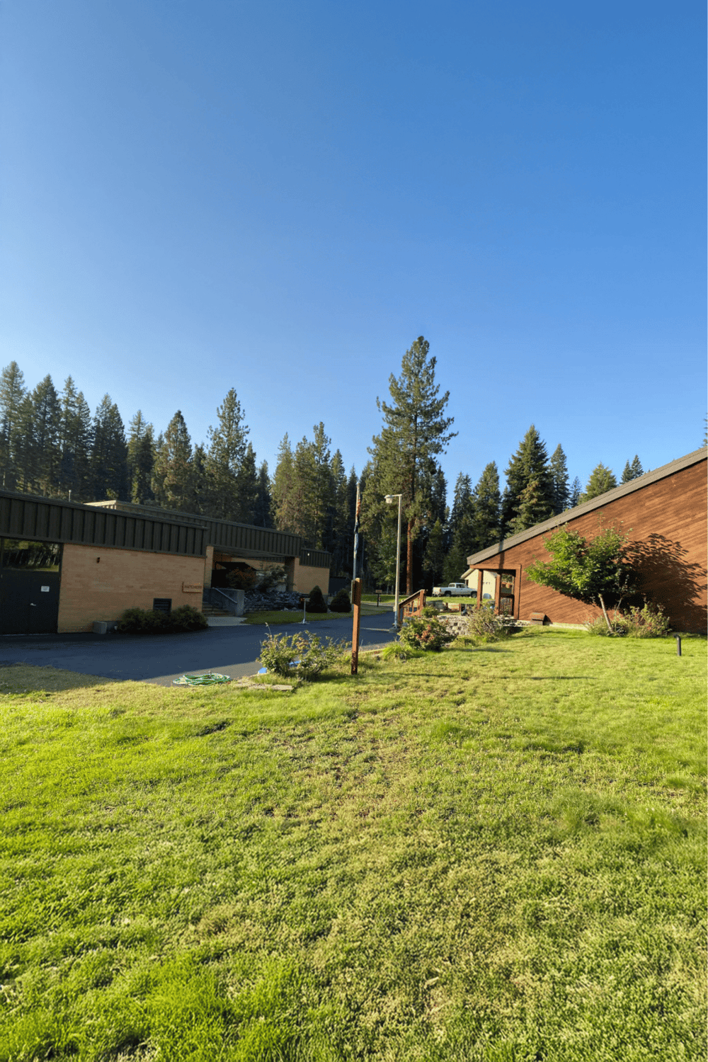 Vast grassy field with trees and buildings under clear blue sky, promoting outdoor activities and navigation services.