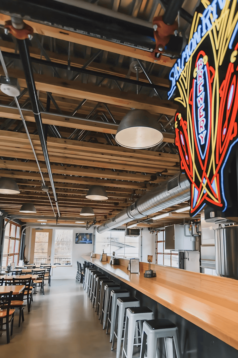 Cozy modern restaurant interior with bar seating, wooden ceiling, and neon signage, perfect for dining and socializing.
