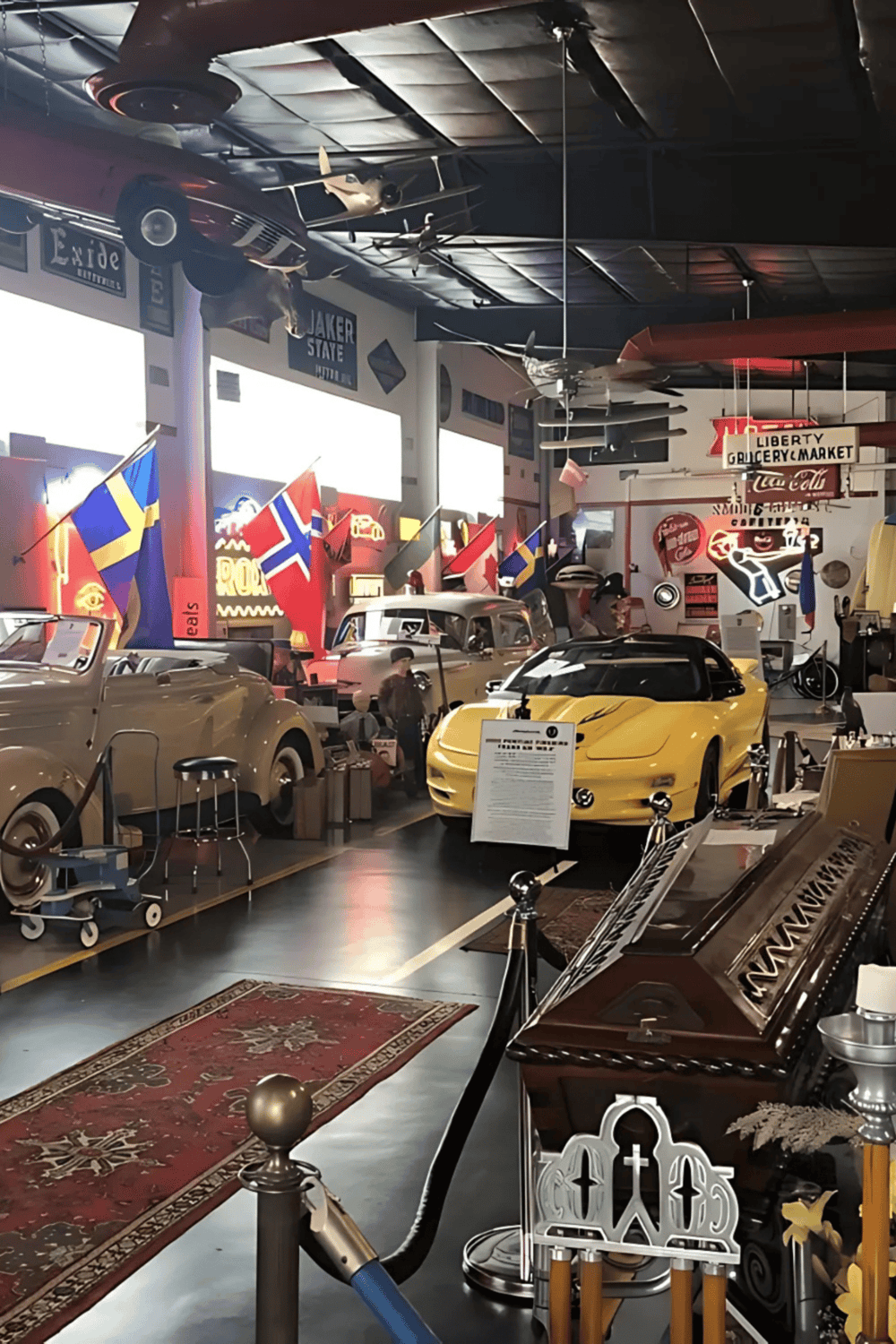 Luxury car museum with vintage and modern automobiles, flags, and aviation memorabilia.