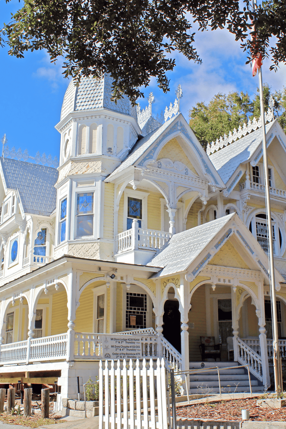 Victorian-style haunted house with intricate white trim and pointed roofs, situated in a park setting.