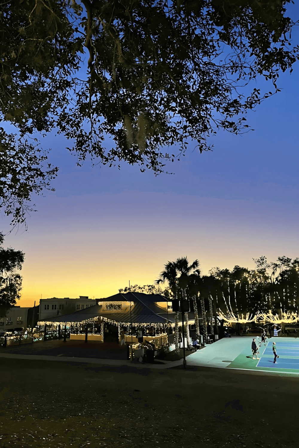 Relaxing park with evening lighting and a basketball court for community recreation.