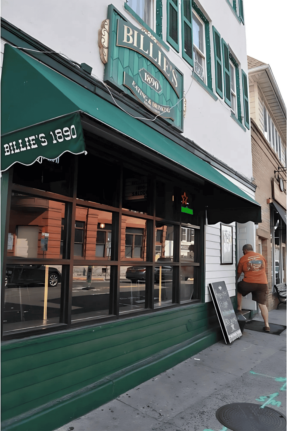 Outdoor bar scene at Billie’s 1890, a historic eatery & drinkery since 1890, with street-side seating and a customer enjoying drinks.