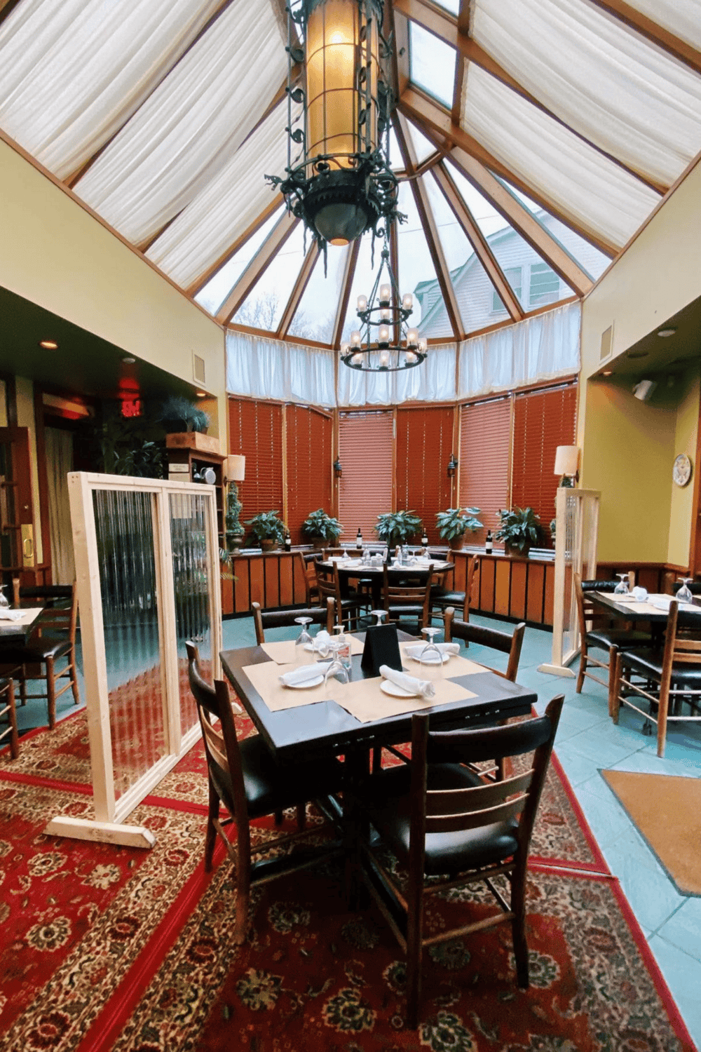 Cozy indoor dining area with a glass skylight, warm wooden accents, and elegant chandelier lighting.