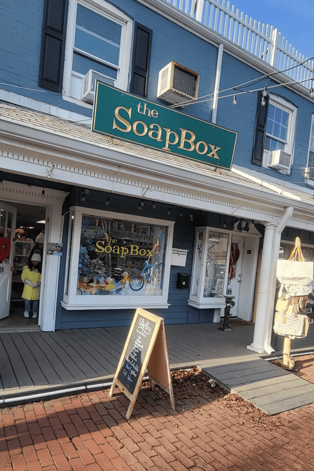 Affordable soap and skincare store, The SoapBox, located in a charming blue storefront with outdoor chalkboard menu.