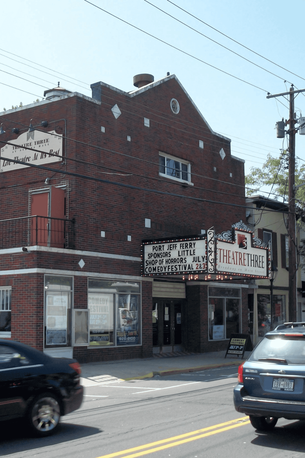 Historic theater building on Main Street with signage for comedy festival and movie screenings.