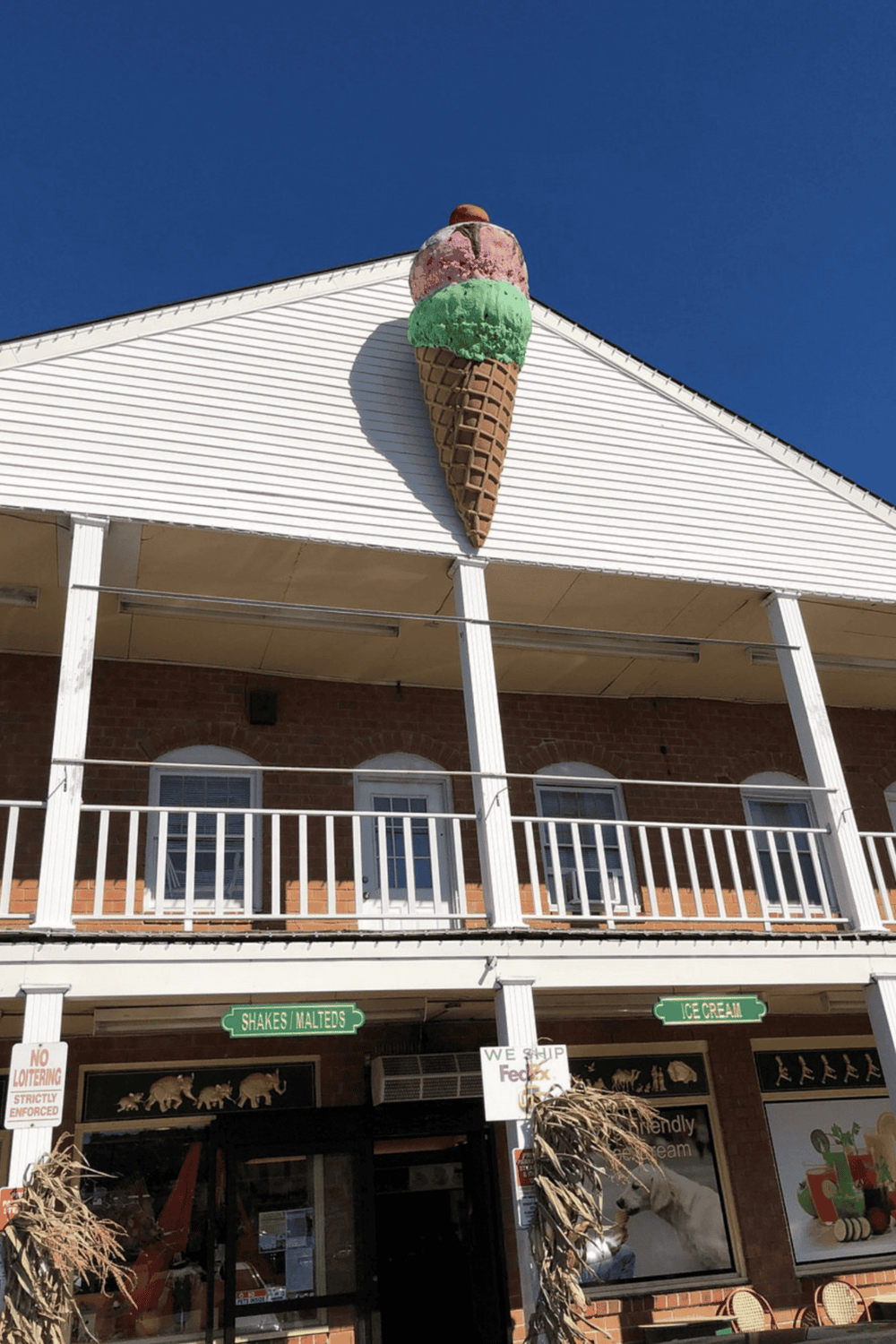Ice cream shop with colorful ice cream cone sign on the building roof, attracting customers seeking frozen treats.