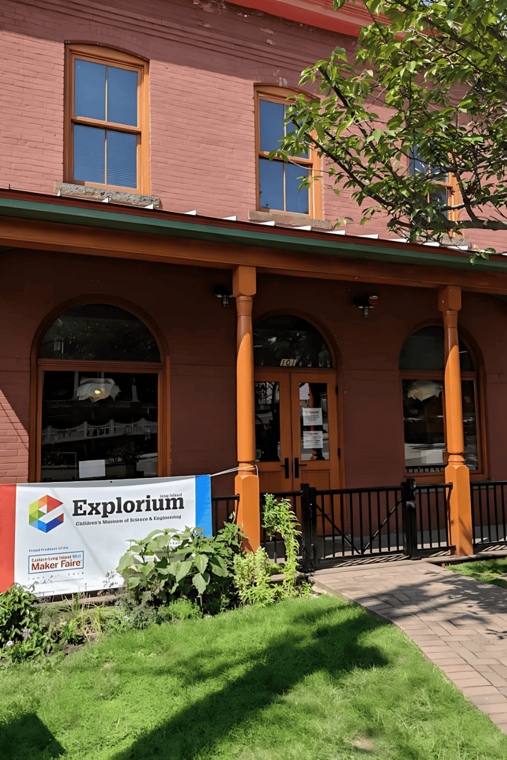 Colorful brick building with large windows and greenery, home to the Explorium Museum in Louisiana.