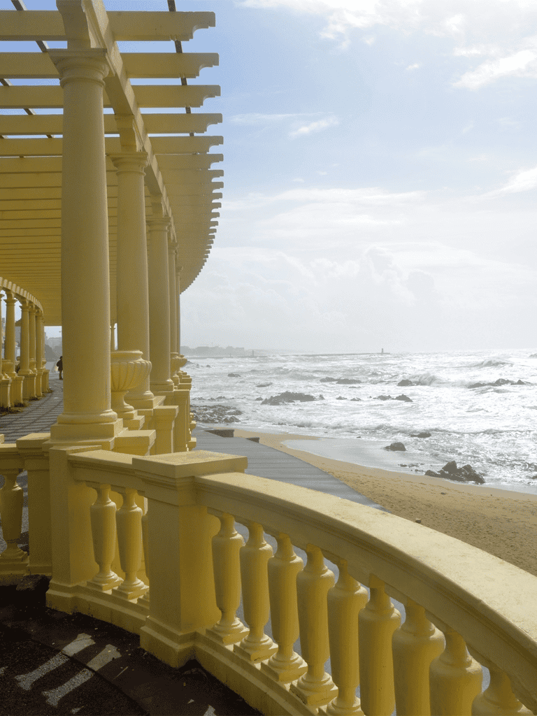 Seaside promenade with yellow columns overlooking ocean view and sandy beach, perfect for coastal walks and scenic drives.