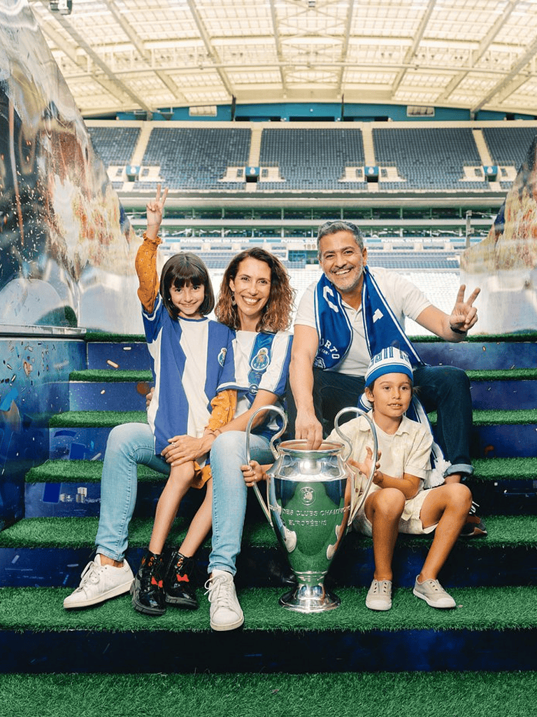 Excited family celebrating Champions League victory at stadium, wearing FC Porto jerseys, with trophy.