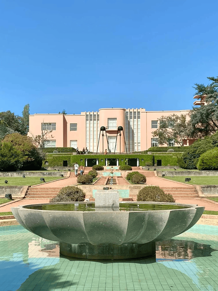 Elegant pink building with modern sculptures and lush landscaping at Quest for Directions.