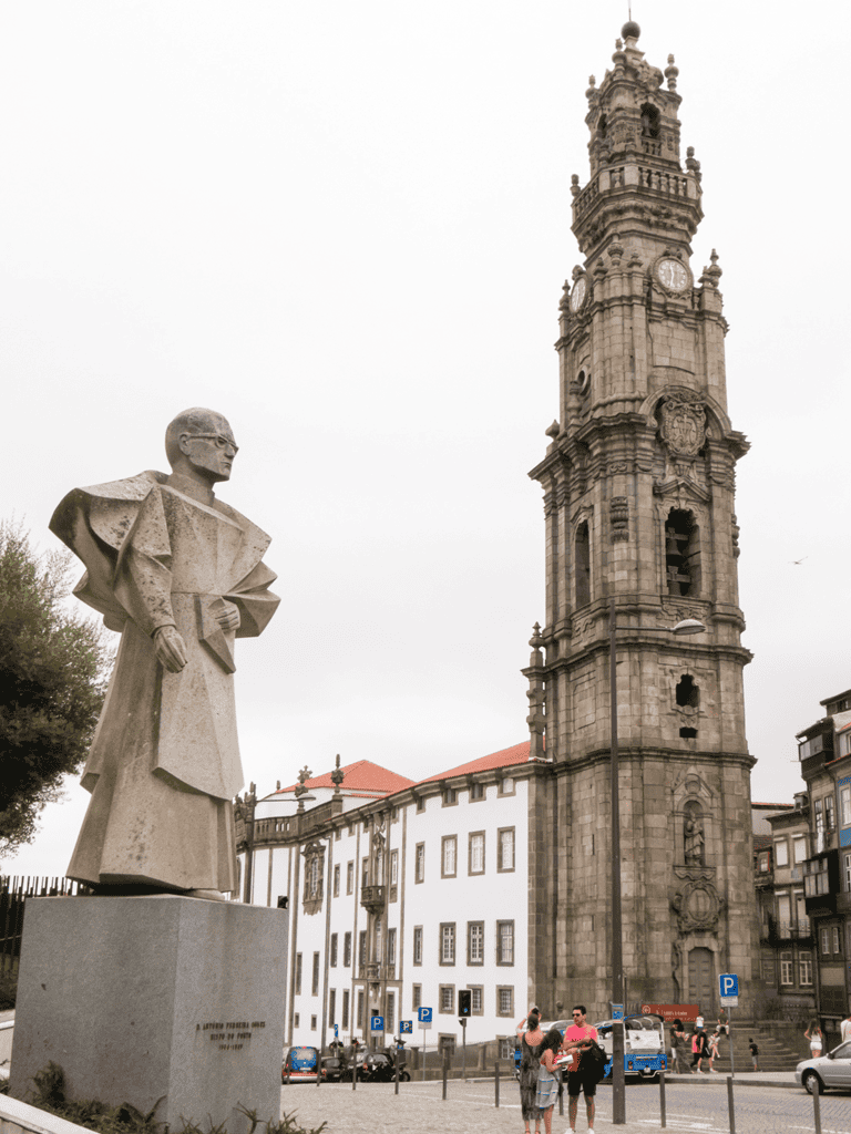 Statue of a historical figure near a tall clock tower in Portugal, popular tourist landmark.