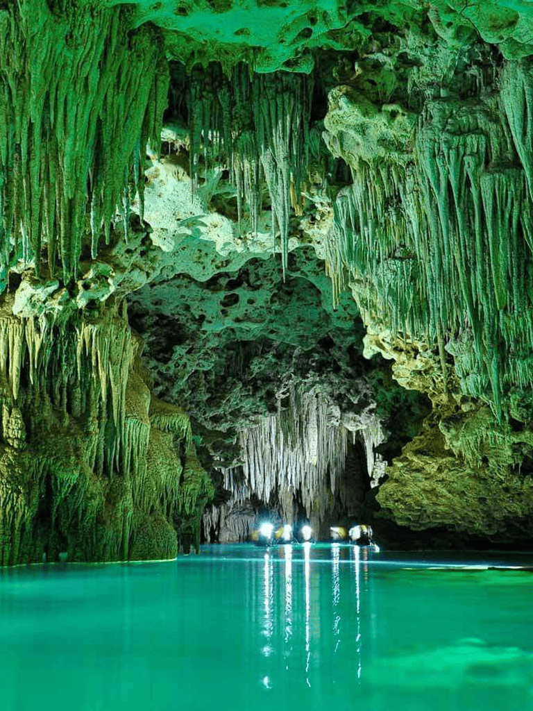 Limestone cave with green stalactites and turquoise water, popular for boat tours and cave exploration.