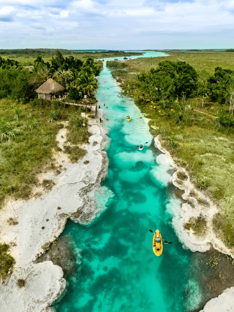 Vibrant turquoise river with kayakers in lush tropical landscape, perfect for adventure travel and nature exploration.