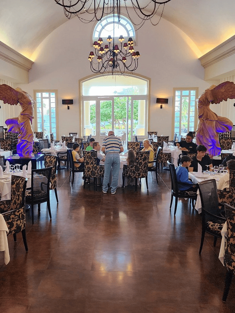 Elegant restaurant interior with children dining and sculptural decor, sunlight streaming through large windows.