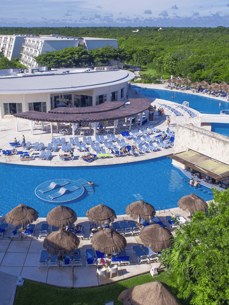 Luxurious hotel pool with sun loungers and thatched umbrellas, tropical scenery, perfect for relaxation.