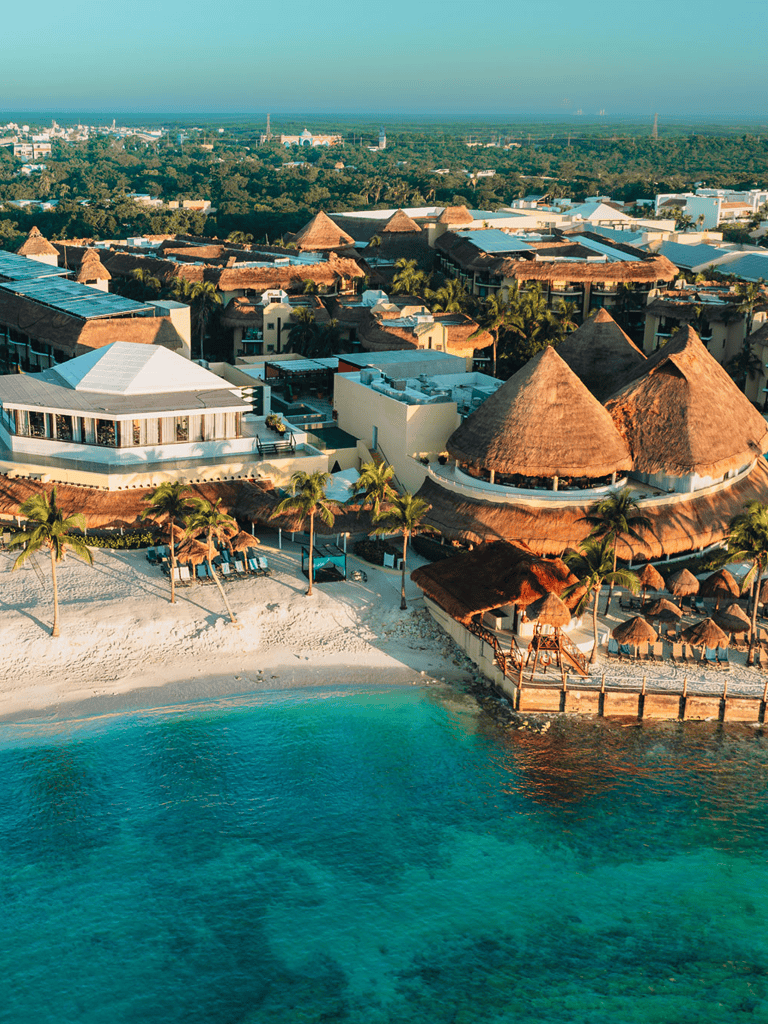 Luxurious beachfront resort with thatched roofs and crystal-clear waters.