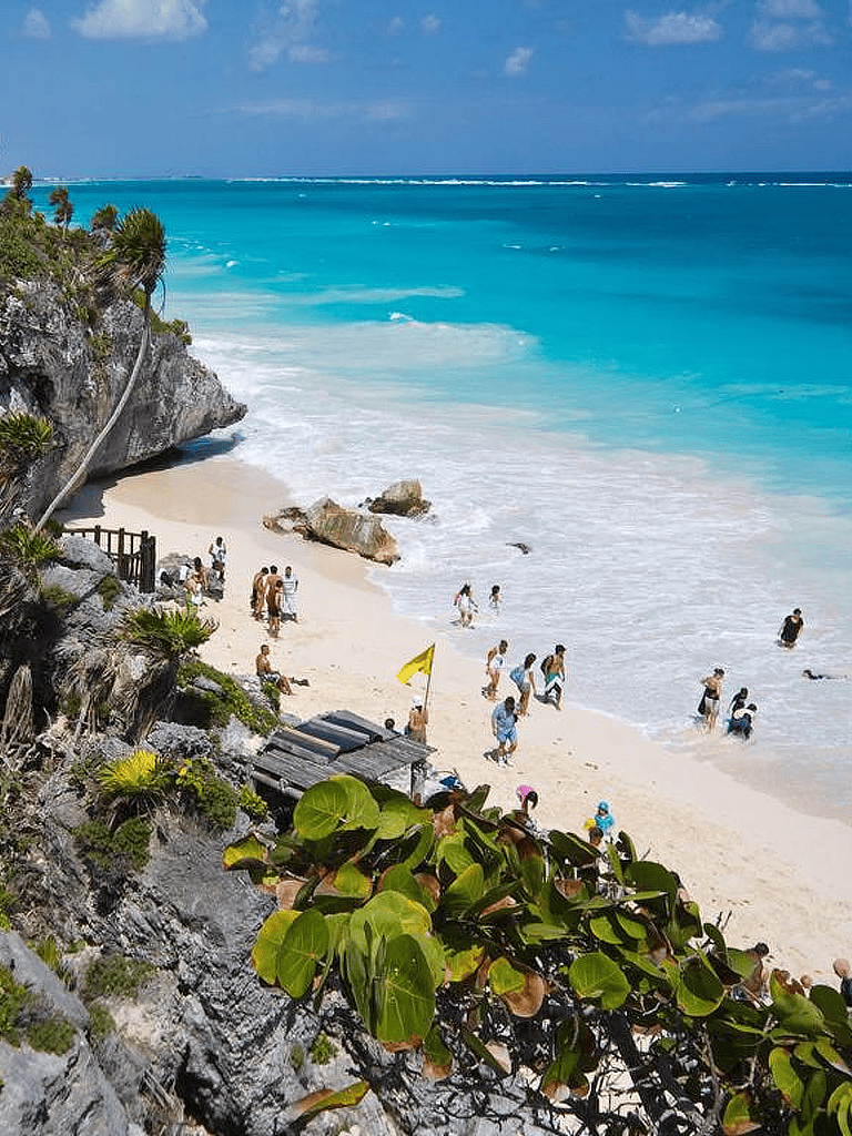 Vibrant beach scene with turquoise waters and visitors enjoying the sunny coast in Mexico.