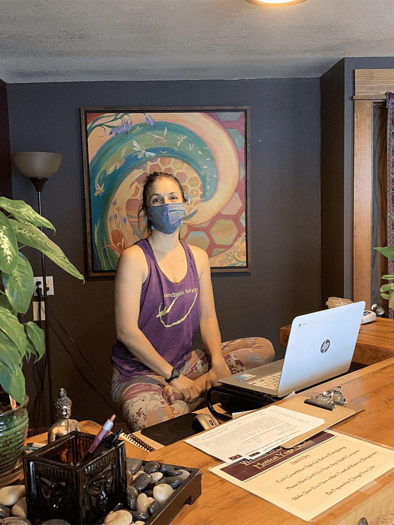 Calming yoga instructor wearing mask in cozy wellness studio.