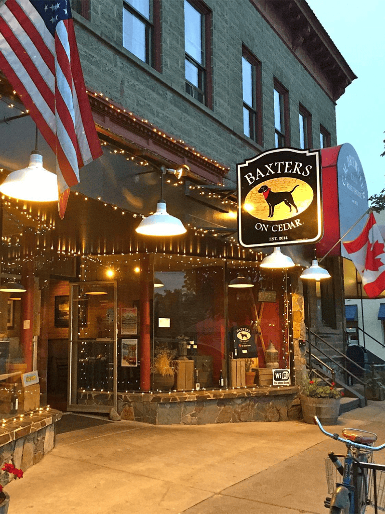 American restaurant, outdoor dining, cozy ambiance, Baxter's on Cedar, historic building, evening lighting, Wi-Fi available, Canadian flags, welcoming atmosphere.