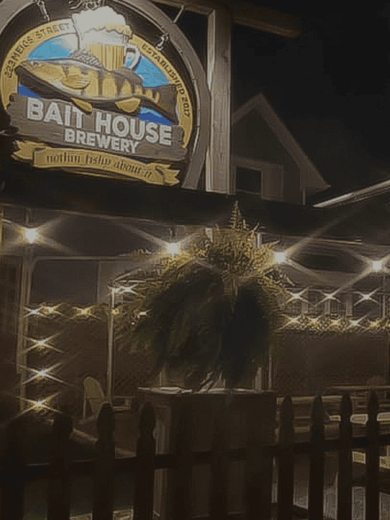 Bat House Beer Garden sign at night with decorative lights and plant display.