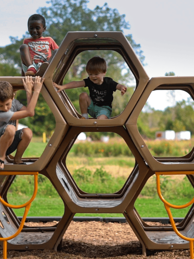 Children playing on a modern playground structure at Quest For Directions outdoor park.