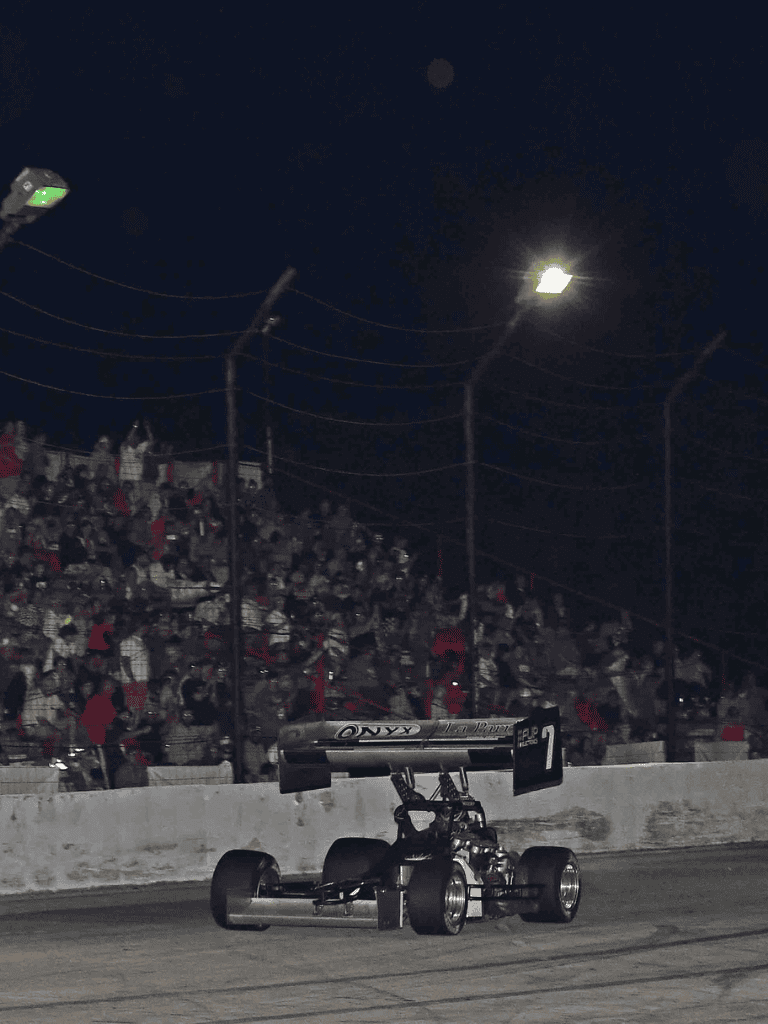 Race car speeding on the track during a nighttime race at QuestForDirections event.