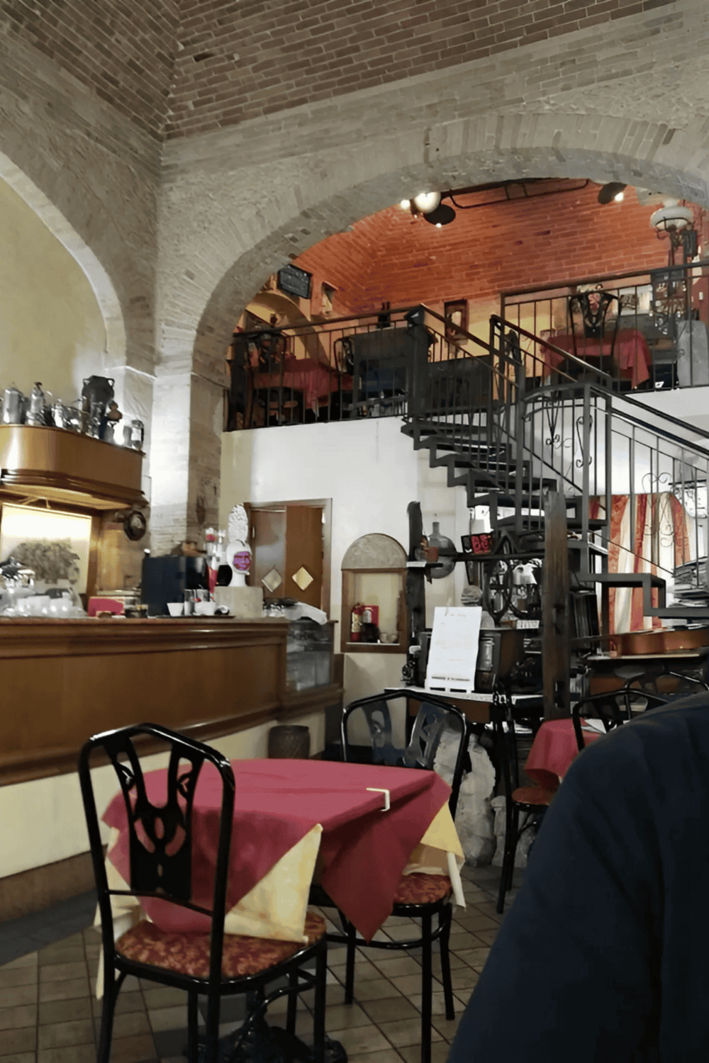 Cozy Italian restaurant interior with arched brick ceilings and upstairs dining area.