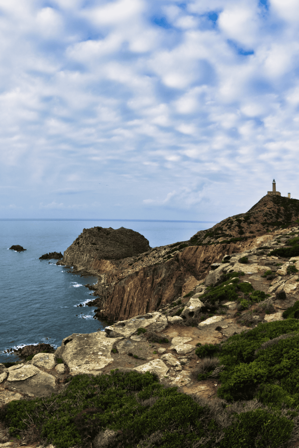 Vivid coastal landscape with lighthouse atop cliffs, scenic ocean views, and rugged shoreline.