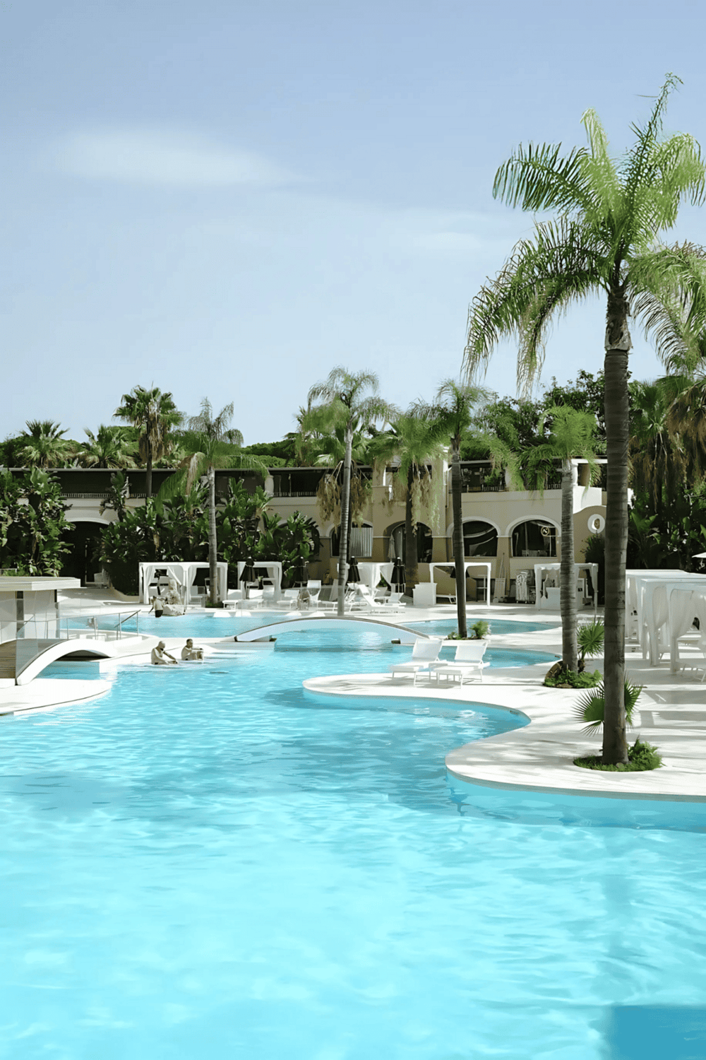 Luxurious hotel pool with palm trees and relaxing lounge chairs, perfect for vacation and leisure.