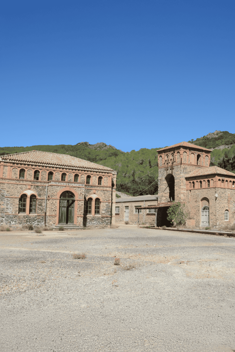 Ancient brick buildings in a rural setting with scenic hills and bright blue sky, highlighting historical landmarks and architecture.