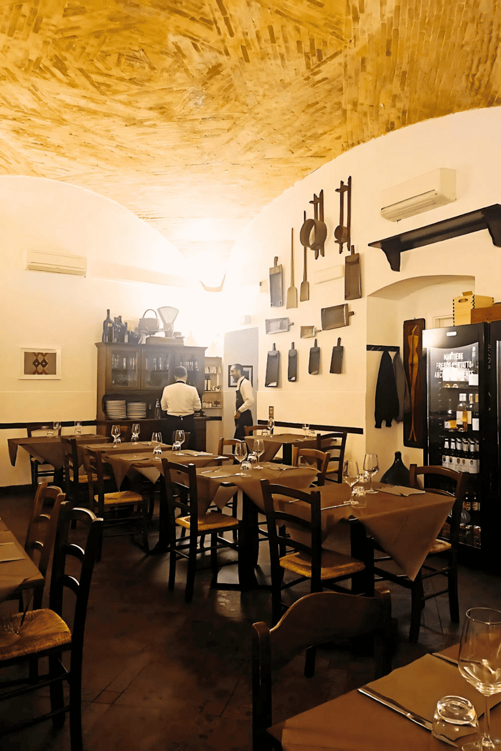 Cozy Italian restaurant interior with wooden ceiling, vintage decor, and neatly set tables for dining experience.
