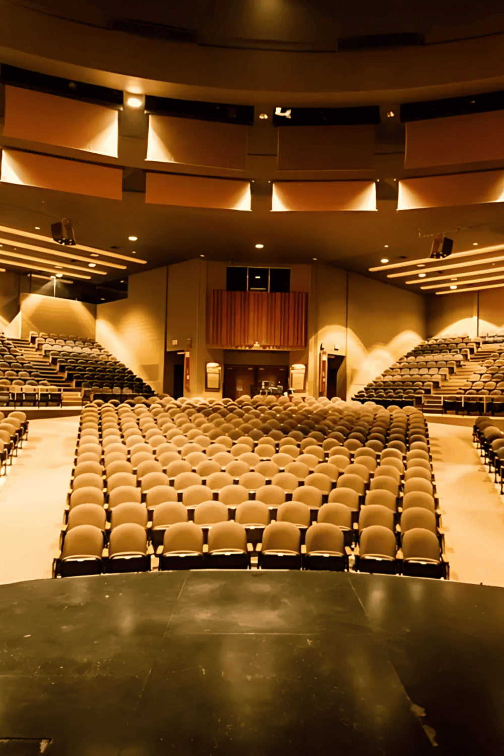 Spacious conference hall with tiered seating and stage, ideal for business events and presentations.