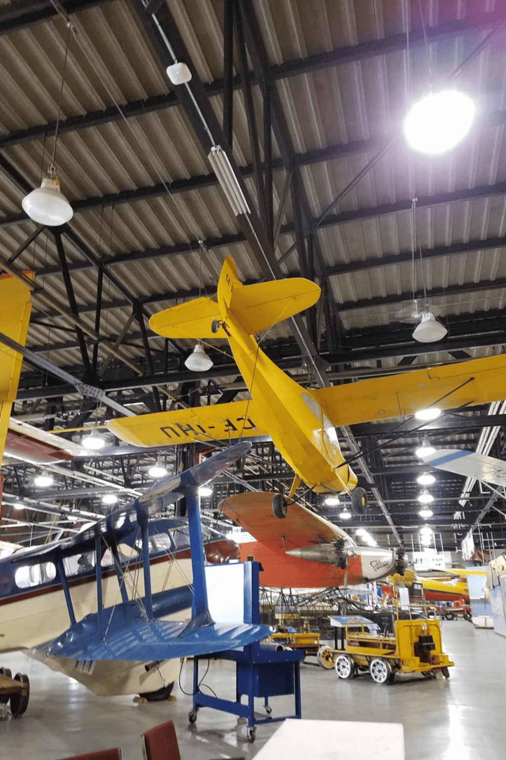 Colorful vintage airplanes hanging inside an aviation museum.