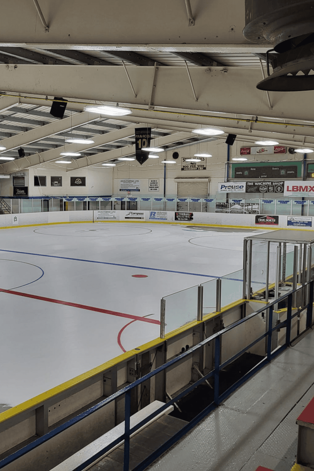 Ice hockey rink with empty ice surface, advertising banners, and seating area.