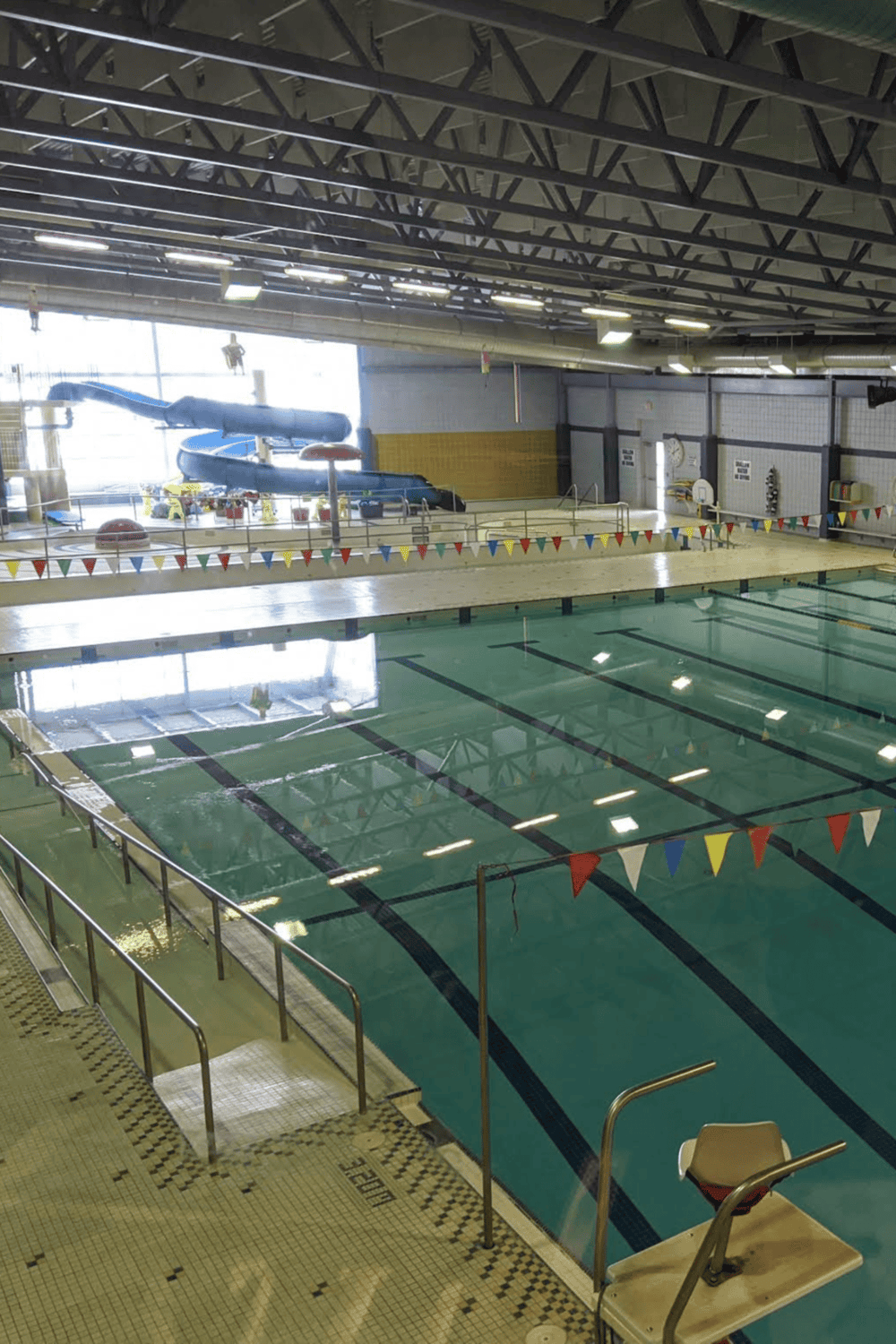 Empty indoor swimming pool with water slide and diving boards, perfect for family fun and recreation.