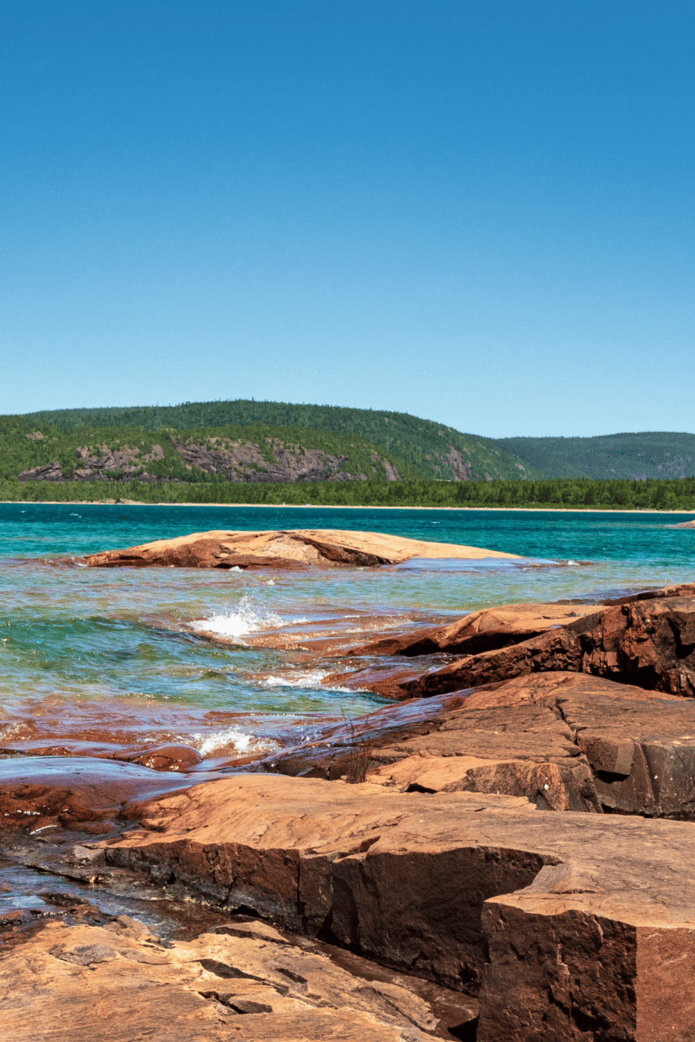 Serene lake with rocky shoreline and forested hills, ideal for outdoor exploration and nature adventures.